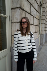 a lady in a black and white knitted striped cardigan with black pants
